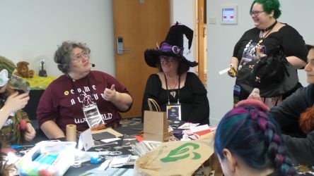 People enjoying a craft workshop, with the event runner explaining how to create custom greeting cards