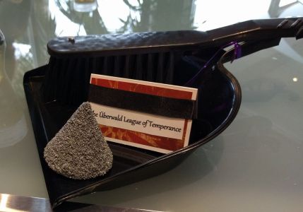 A dustpan with a small pile of dust, and a card saying "The Uberwald League of Temperance" (from the 2017 Australian Discworld Convention)