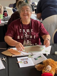 A smiling woman learning about book binding at the craft workship at Nullus Anxietas 9.