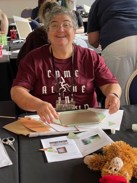 A smiling woman learning book binding at the craft workshop at Nullus Anxietas 9